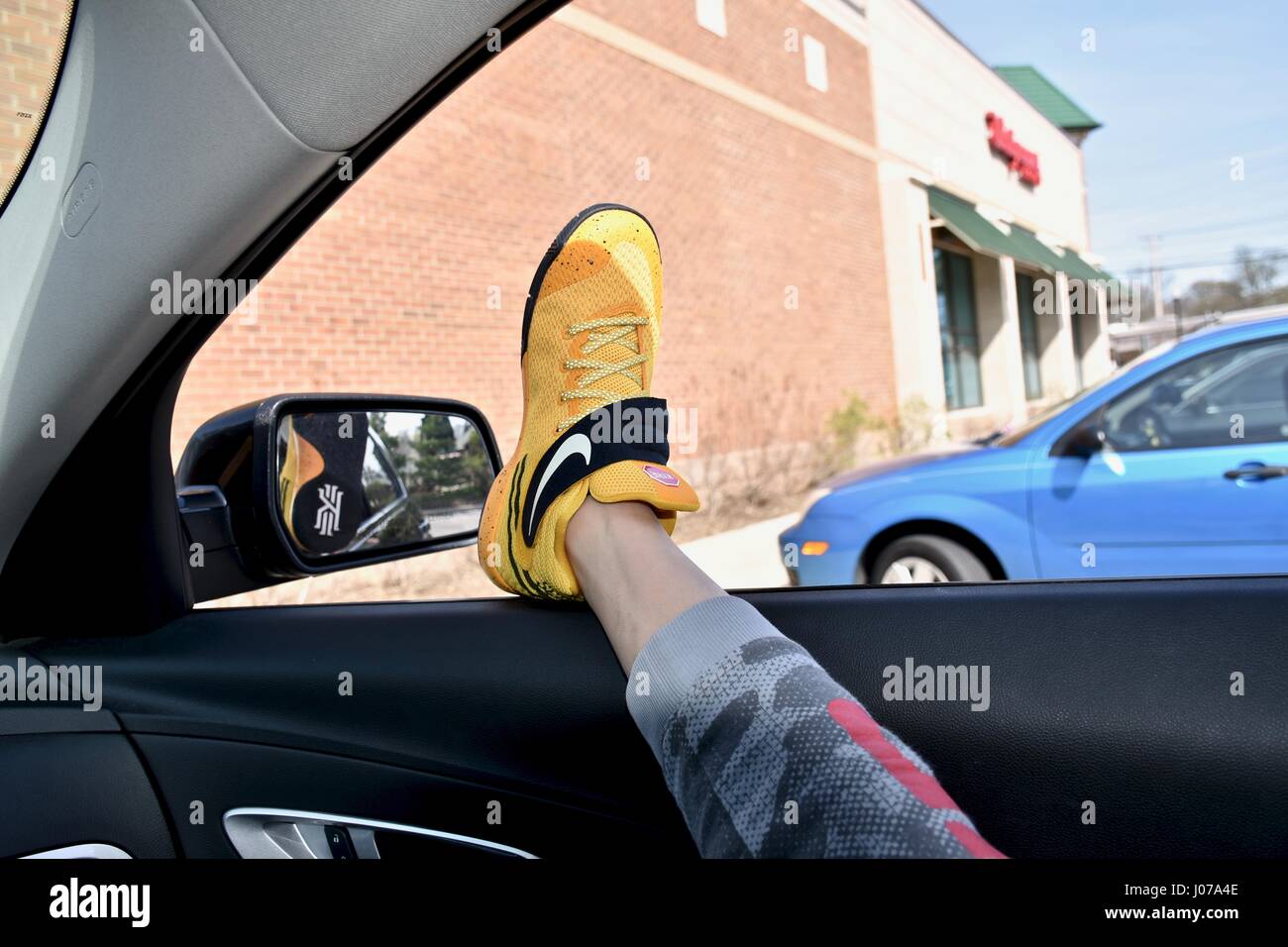 Hanging feet with Nike shoes out car window Stock Photo