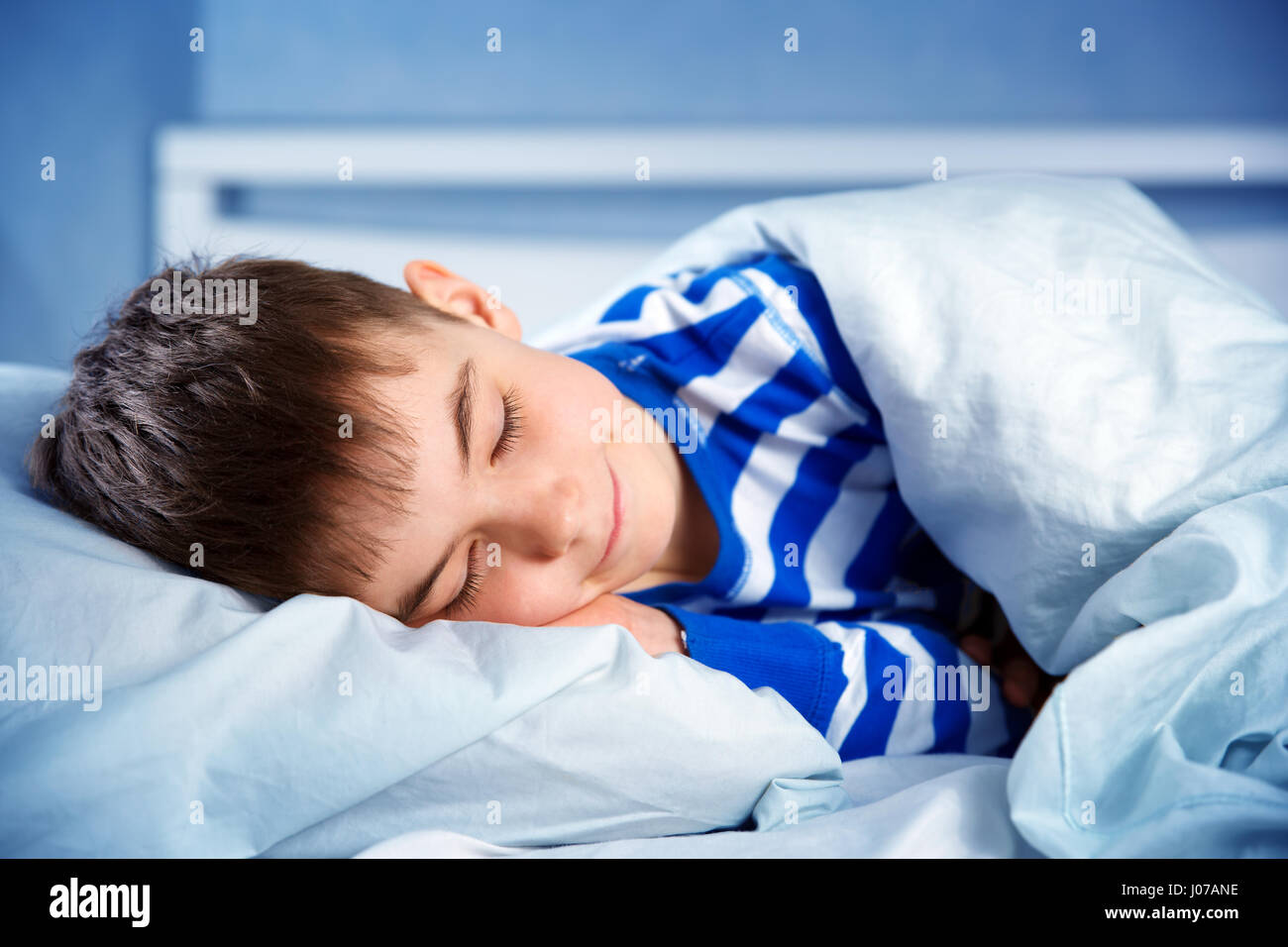 Boy sleeping in bed in pajamas Stock Photo Alamy