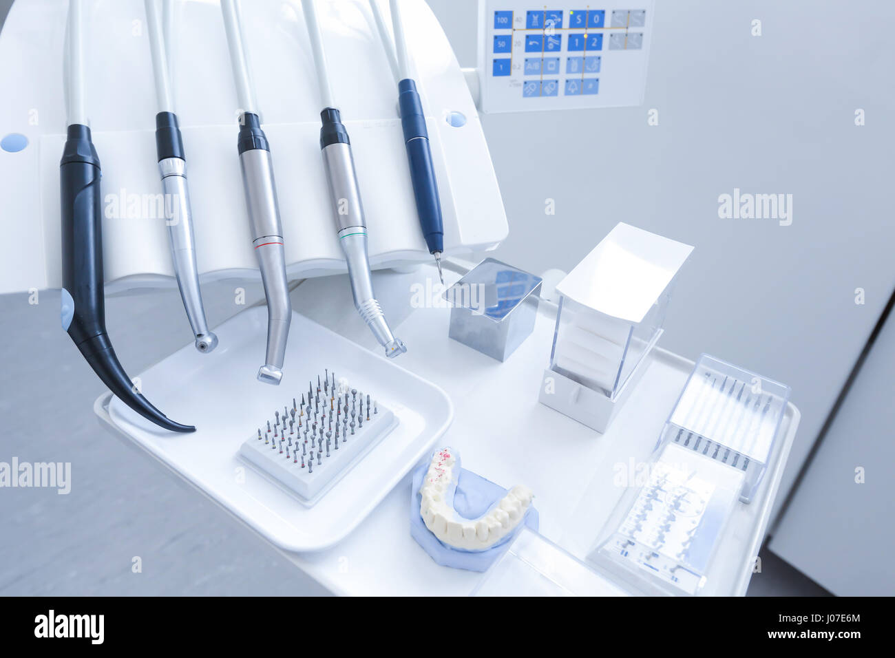 Dental practice - specialist tools, drills, handpieces and laser with polish nozzles, drill nozzles and denture model in the foreground Stock Photo