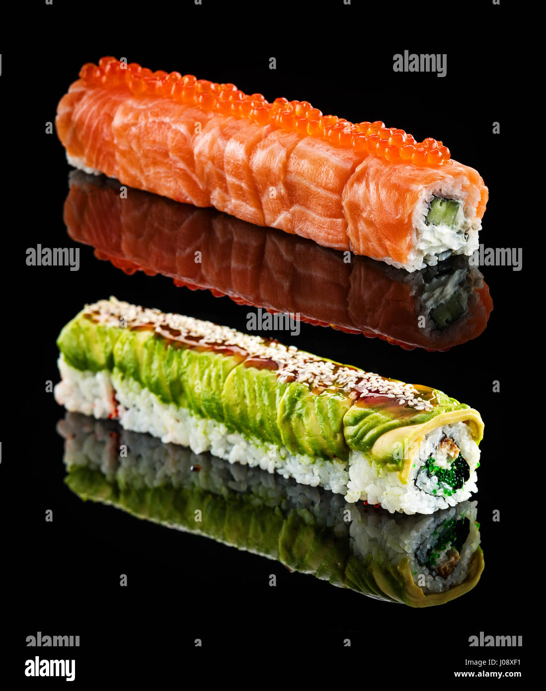 Dragon roll with salmon and red caviar and dragon roll with avocado and flying fish roe over black background Stock Photo