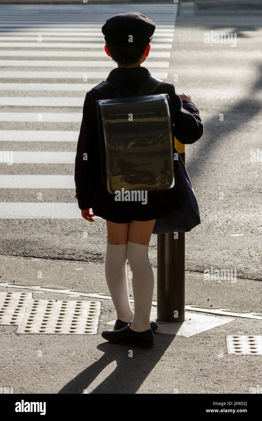 A Japanese school boy wearing an old fashioned school uniform and carrying  a satchel waits to cross the road in Yokohama, Kanagawa, Japan Stock Photo  - Alamy