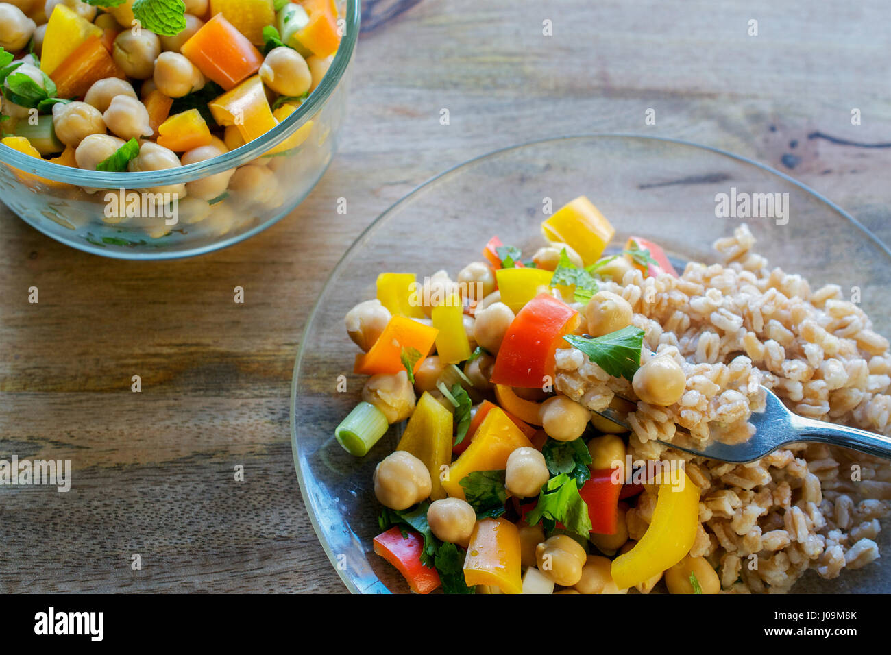 A fork picking up a portion of farro, and garbanzo bean salad, with a