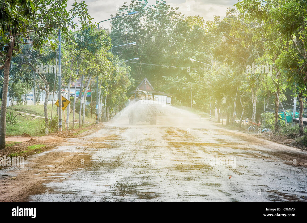 A water truck sprays water on a fresh fill layer of soil and rock for a ...