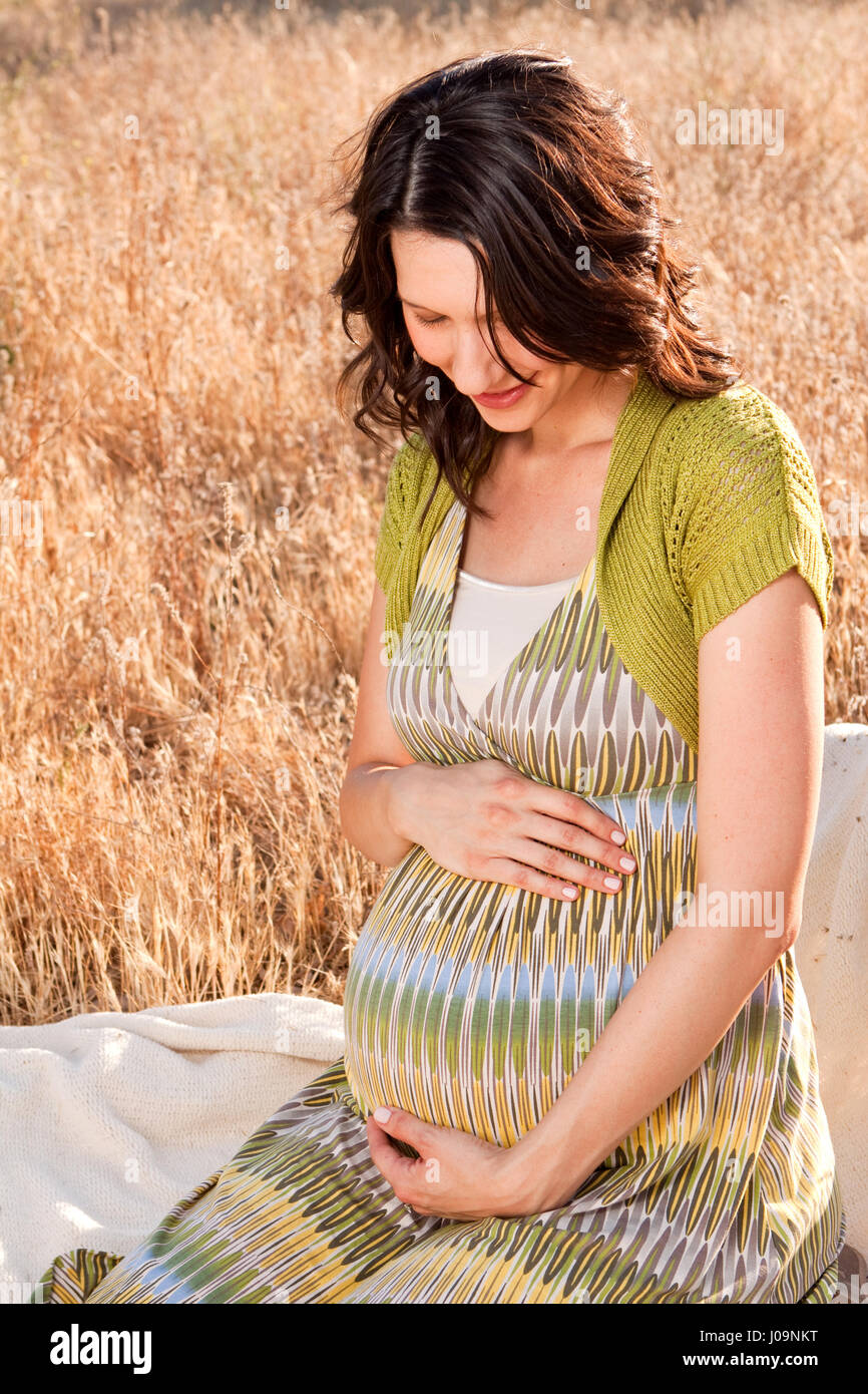 Pregnant woman ouside holding her belly Stock Photo - Alamy