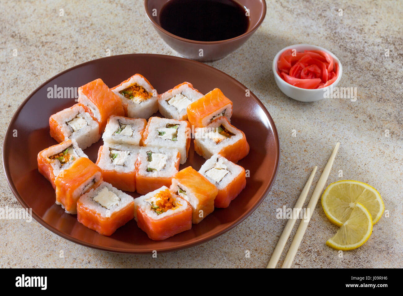 Sushi set on a stone background - roll Philadelphia classic, roll Cheese salmon and roll Jamaica with pickled ginger and soy sauce. Stock Photo