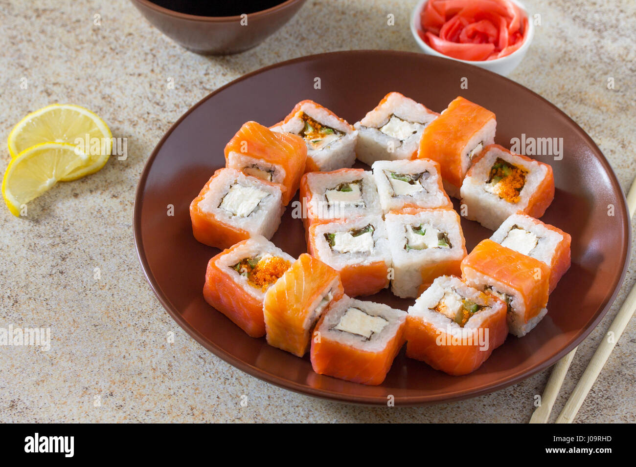 Sushi set on a stone background - roll Philadelphia classic, roll Cheese salmon and roll Jamaica with pickled ginger and soy sauce. Stock Photo