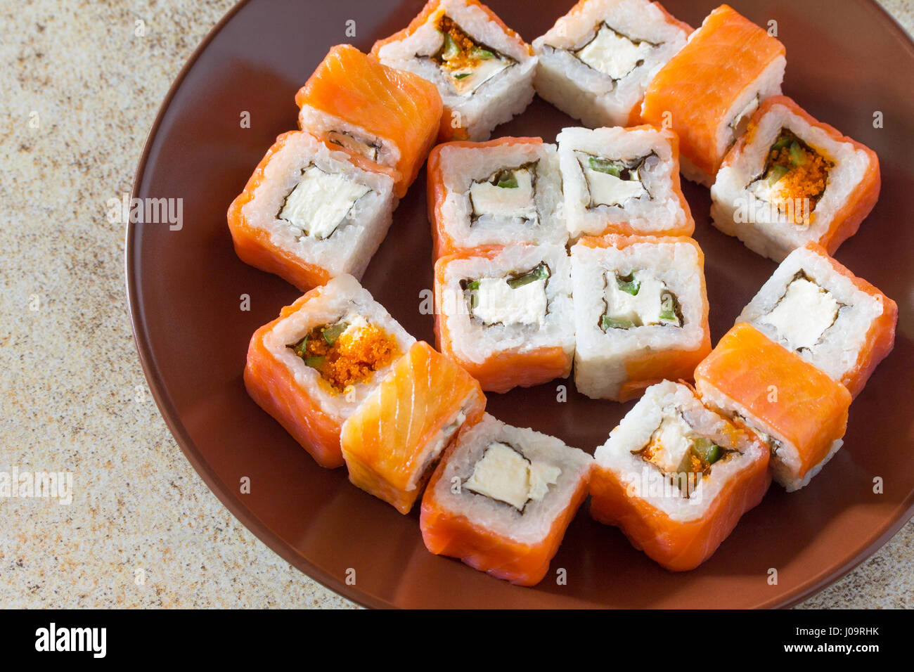 Sushi set on a stone background - roll Philadelphia classic, roll Cheese salmon and roll Jamaica with pickled ginger and soy sauce. Stock Photo