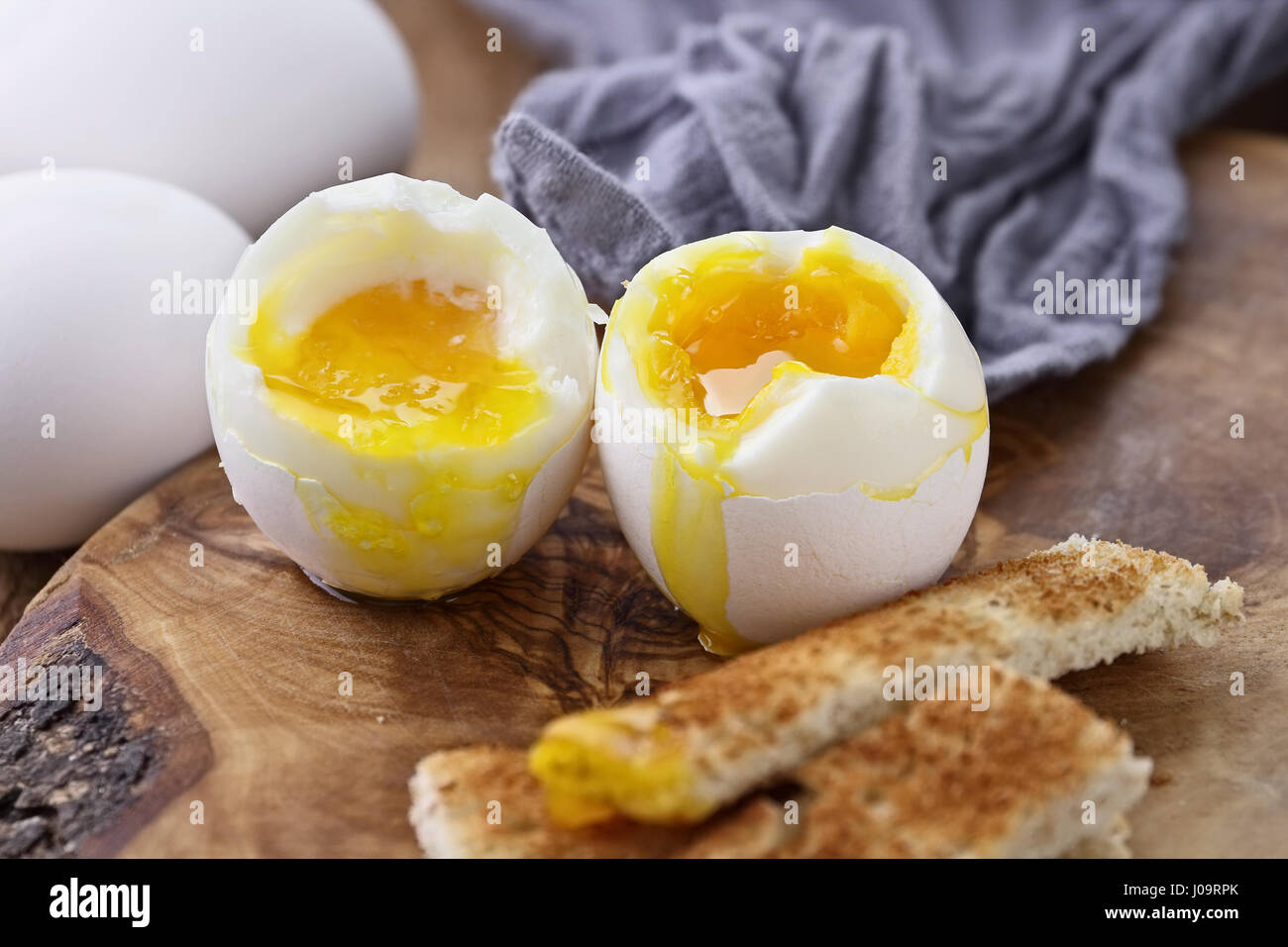 Two soft boiled eggs with toast soldiers against a rustic background
