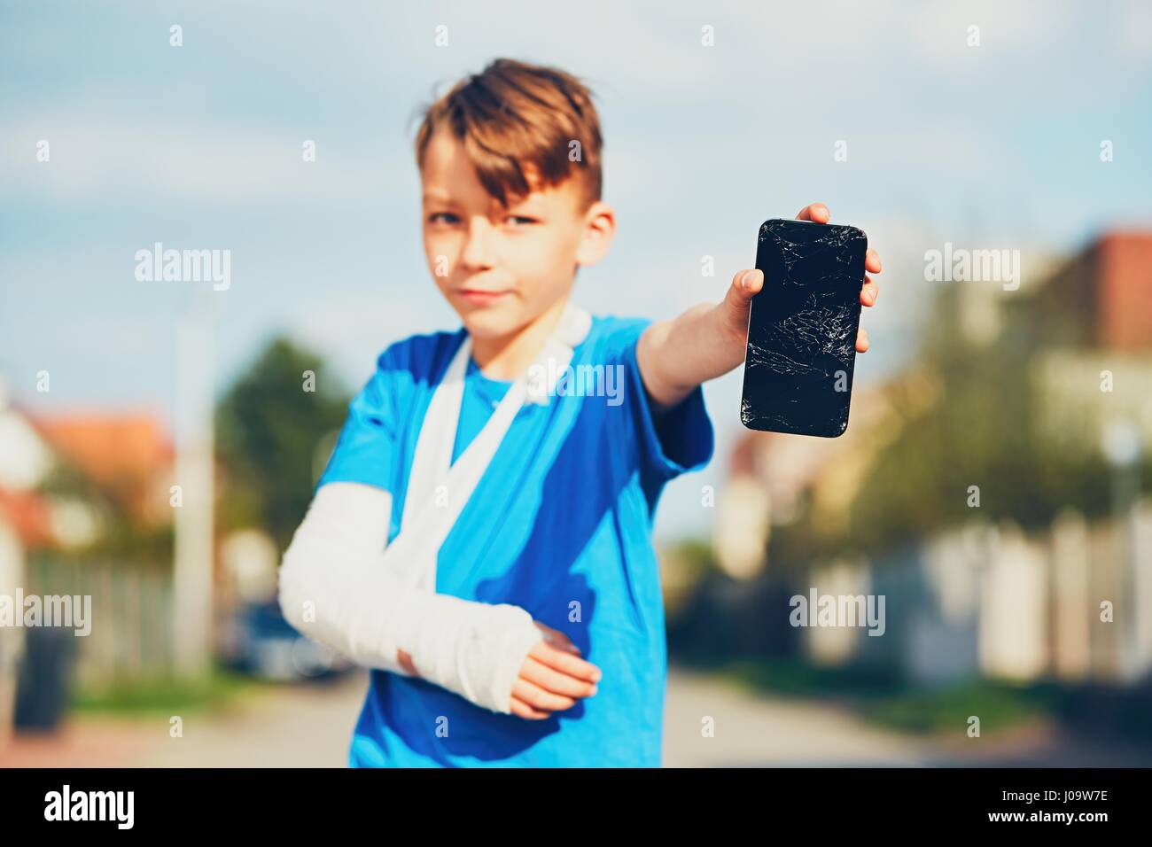 Little boy with broken hand injured after accident showing damaged mobile phone Stock Photo