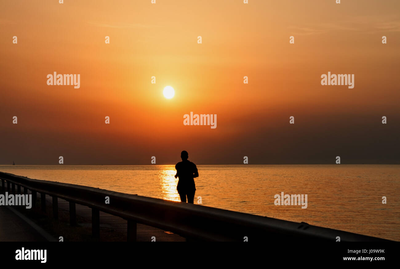 Silhouette of man running along the sea at sunset Stock Photo - Alamy