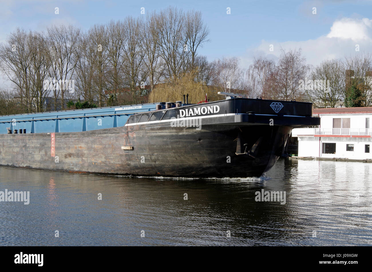Bulk carrier barge passing modern house boats on Schinkel canal in Amsterdam-Zuid, Netherlands Stock Photo