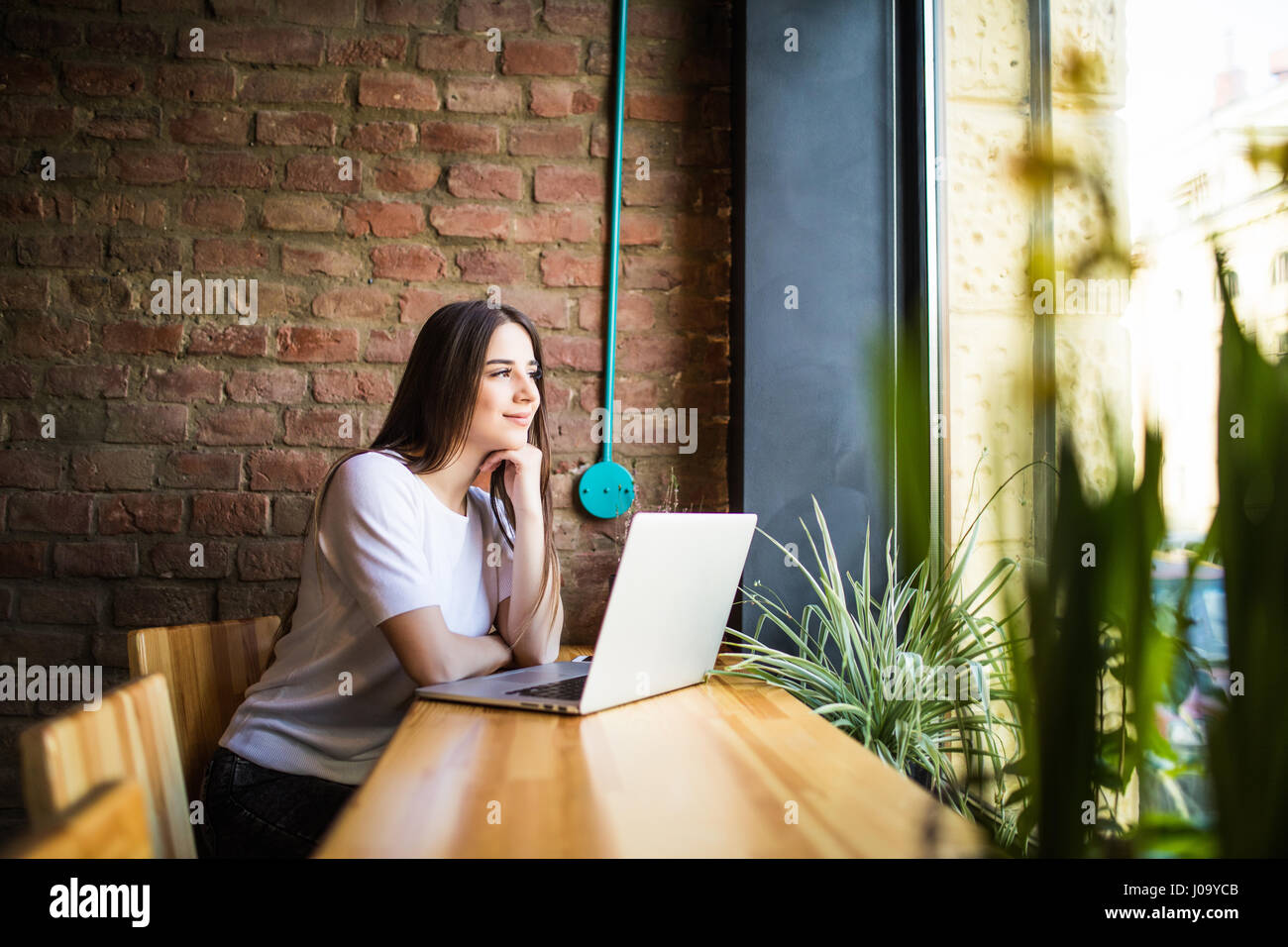 Side view of a young woman using laptop in cafe Stock Photo