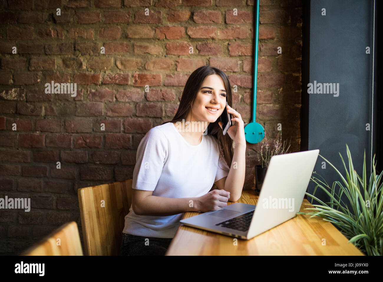 Caucasian woman using laptop and mobile phone behind of a cafe Stock ...