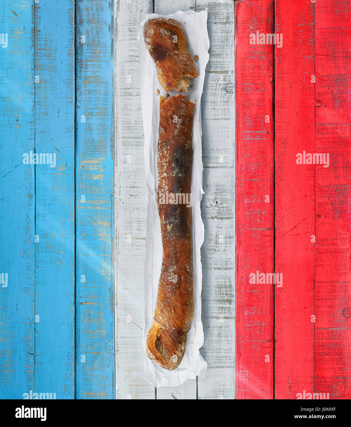 A traditional french baguette over a rusticwooden  table with the colors of France flag. Stock Photo