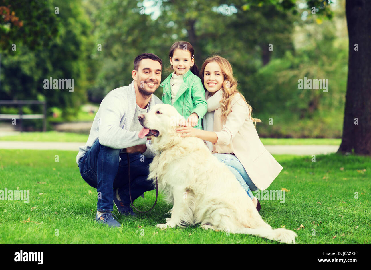 happy family with labrador retriever dog in park Stock Photo