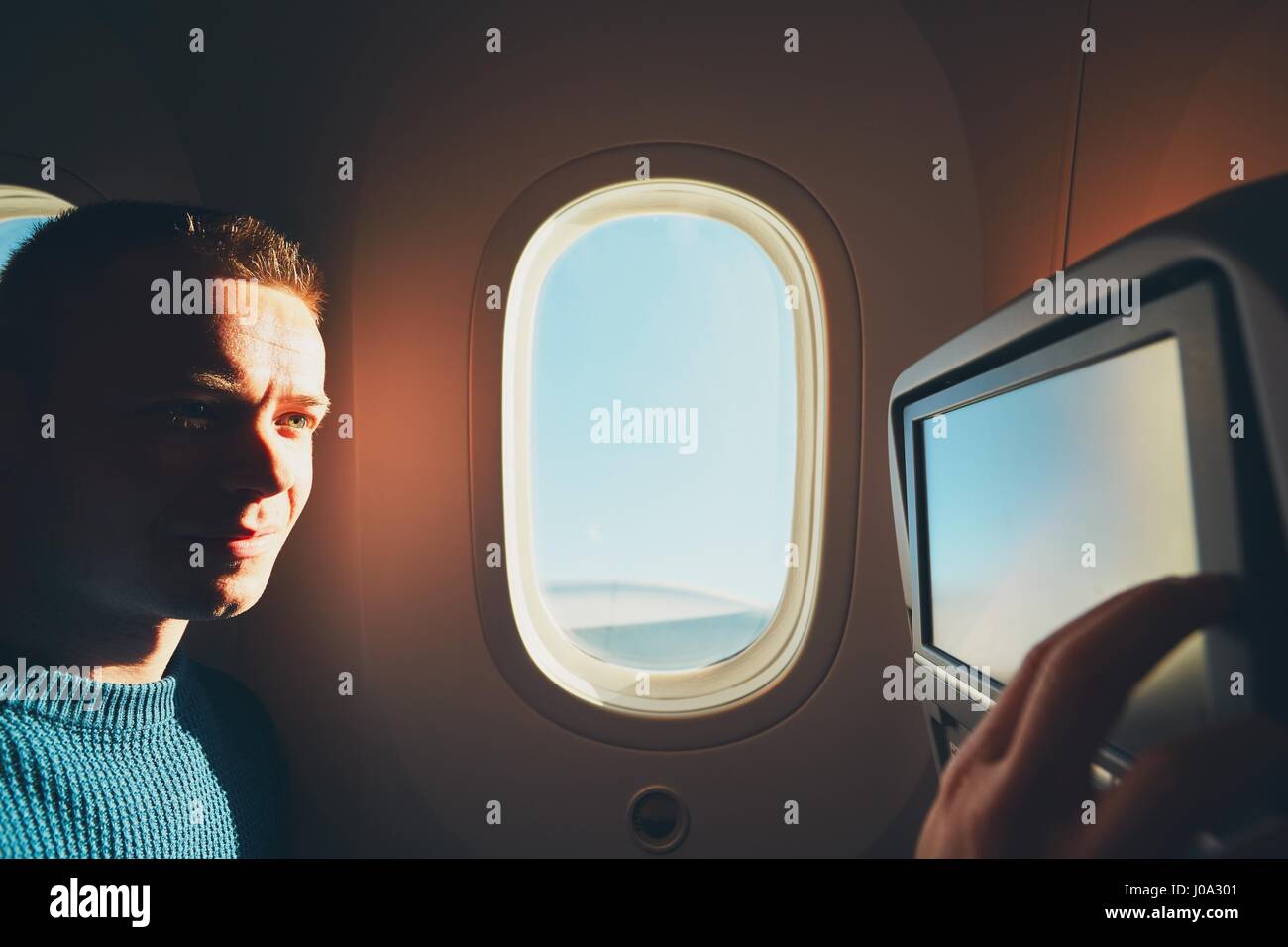 Comfortable traveling by airplane. Young passenger enjoying his journey inside an airplane. Stock Photo
