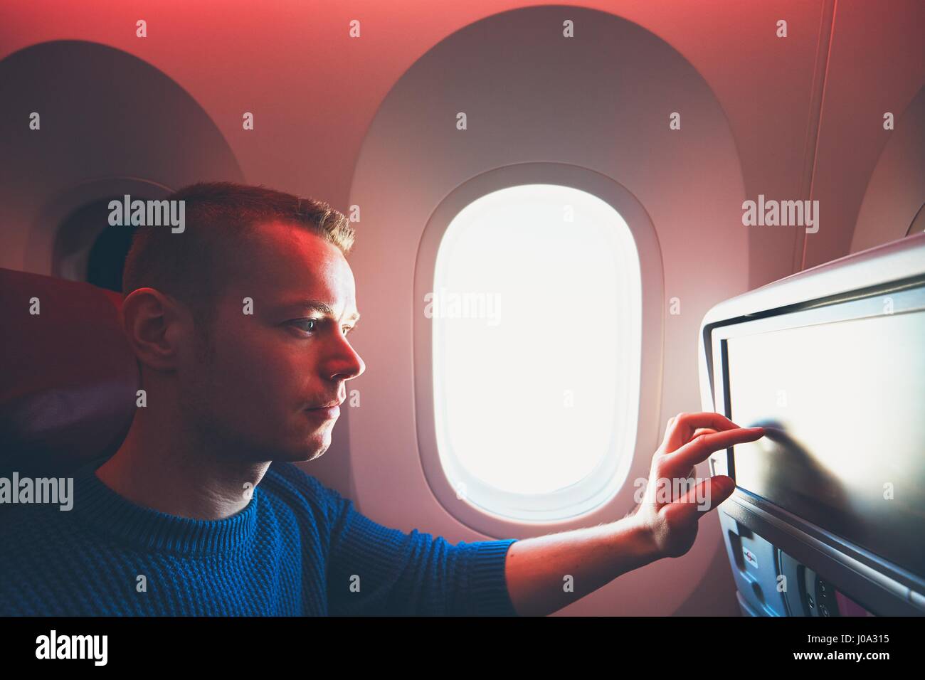 Comfortable traveling by airplane. Young passenger enjoying his journey inside an airplane. Stock Photo