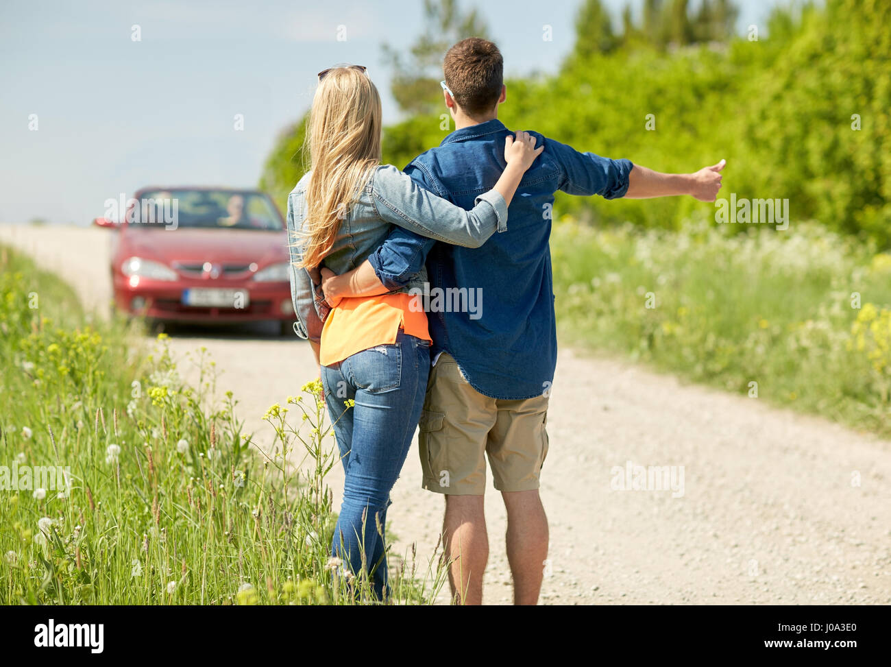 couple hitchhiking and stopping car on countryside Stock Photo