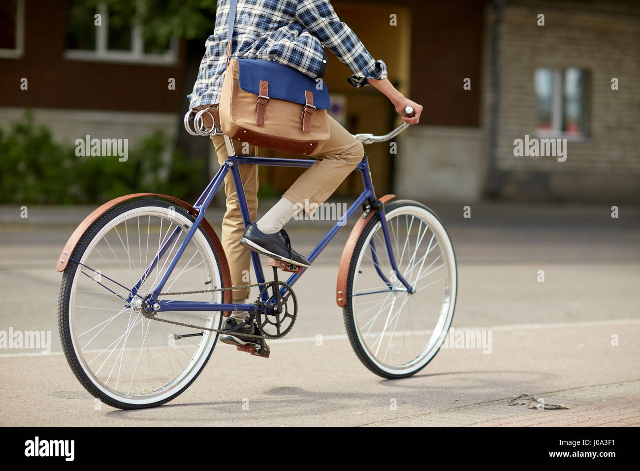 young hipster man with bag riding fixed gear bike Stock Photo