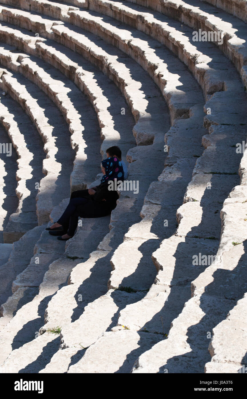 A muslim couple seated on the bleachers of the Roman Theater of Amman, a 6.000 seat theatre dating back to the Roman period Stock Photo