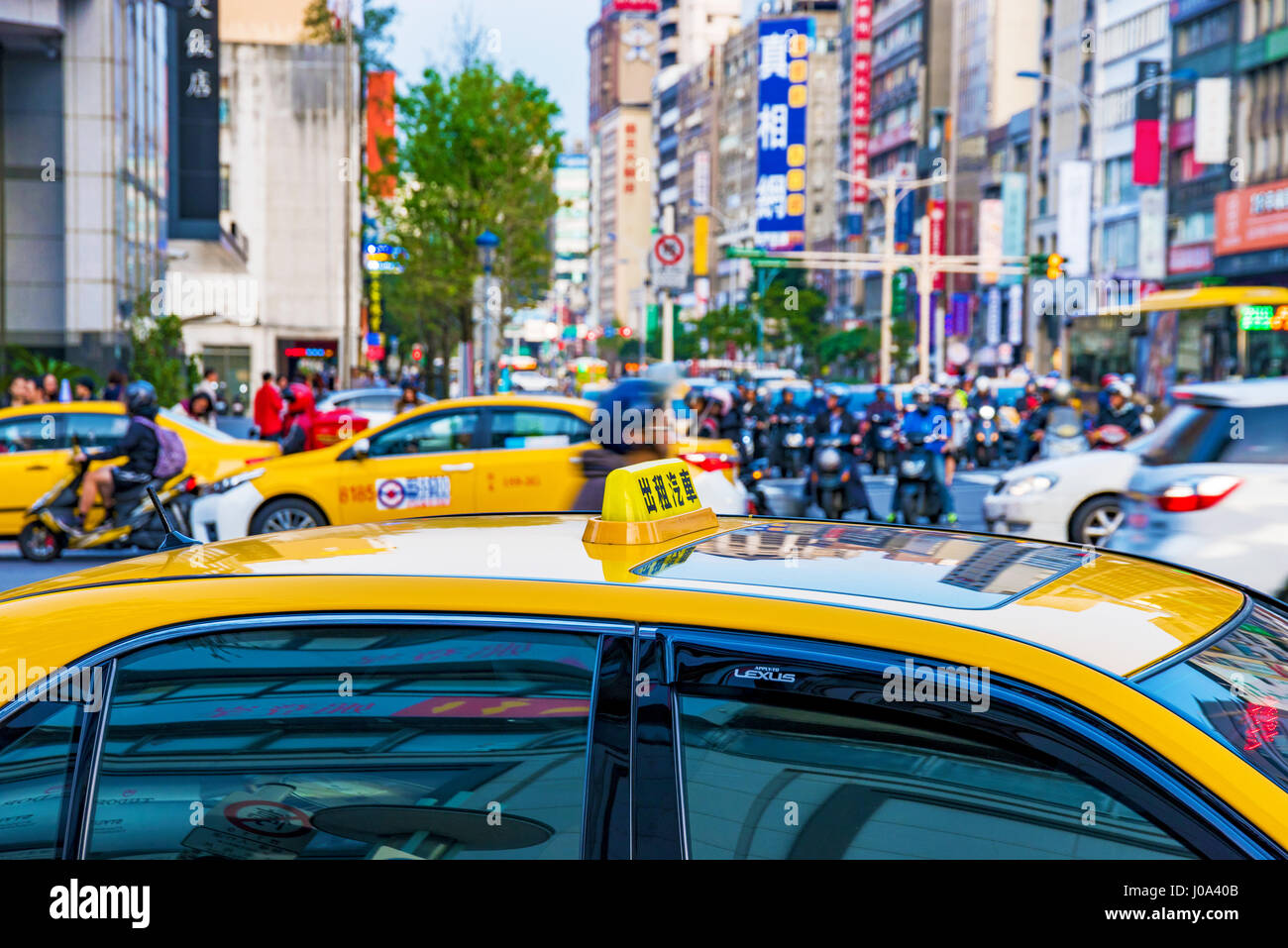 Taxi in the downtown area of Zhongshan with a busy city scene of cars and traffic in the background Stock Photo