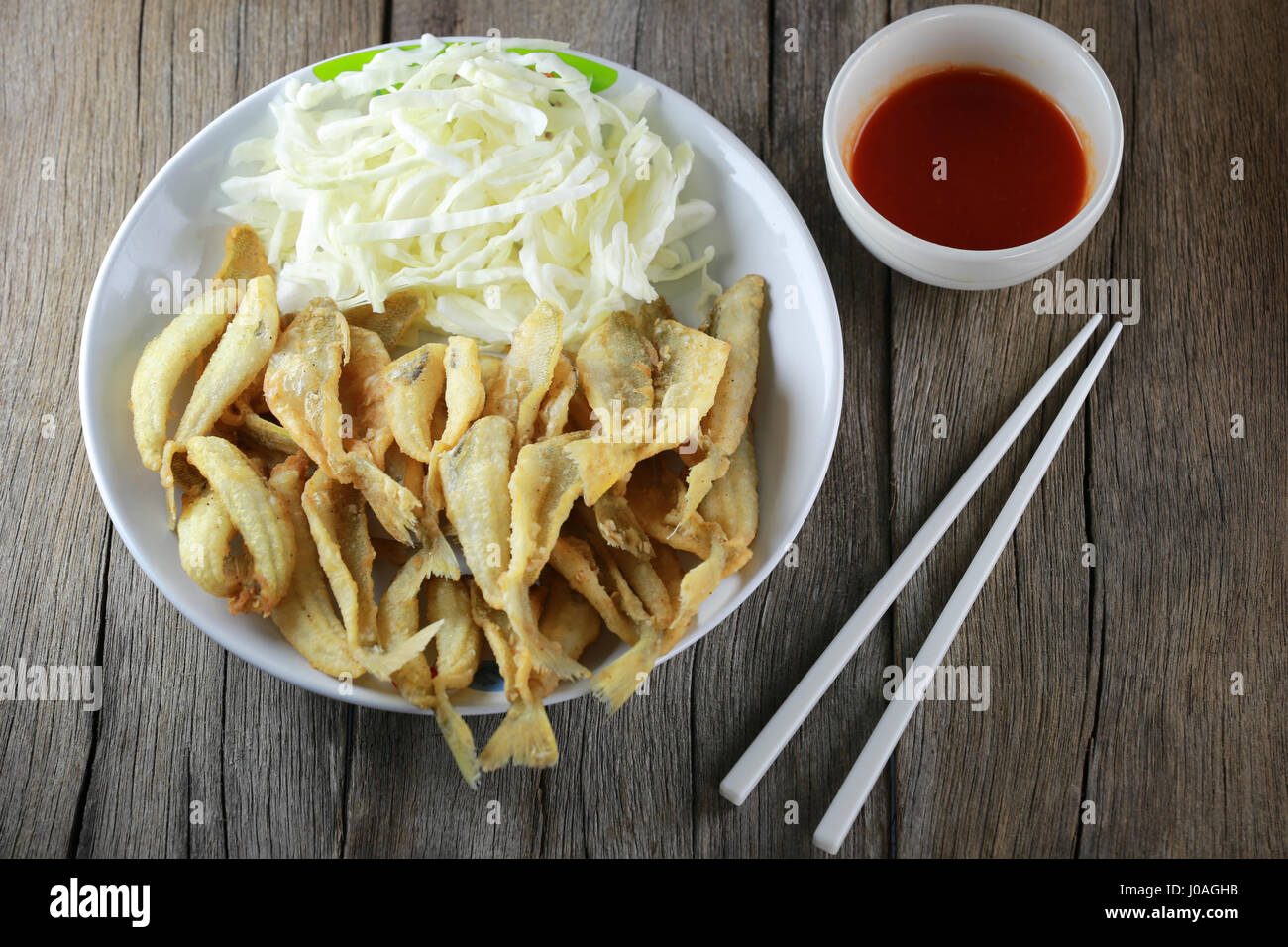 Fried Sillago fish of seafood in white dish and fresh cabbage on wooden background. Stock Photo