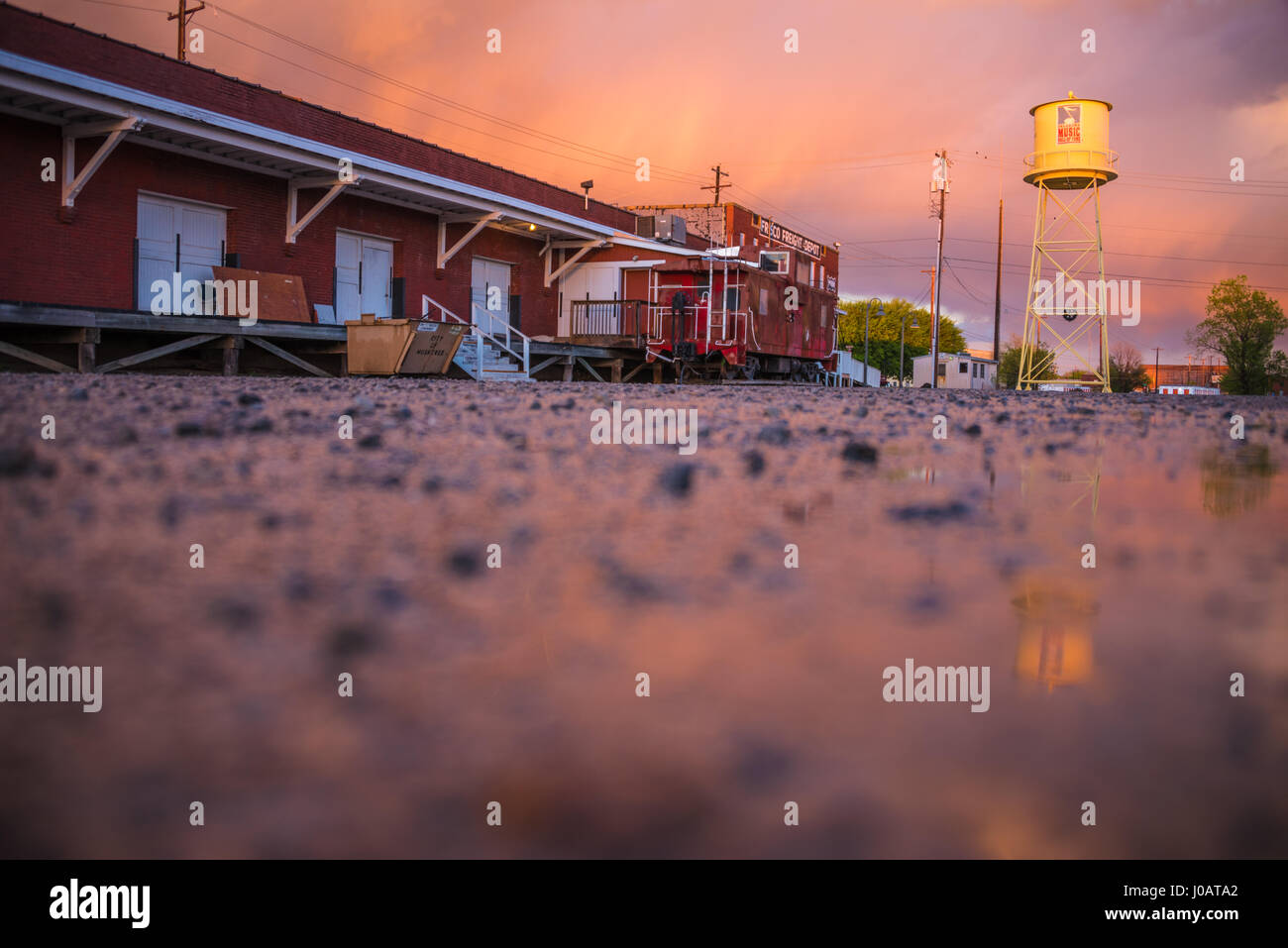 Train car and water tower at the Oklahoma Music Hall of Fame under a colorful sunset sky in Muskogee, Oklahoma's Depot District. Stock Photo