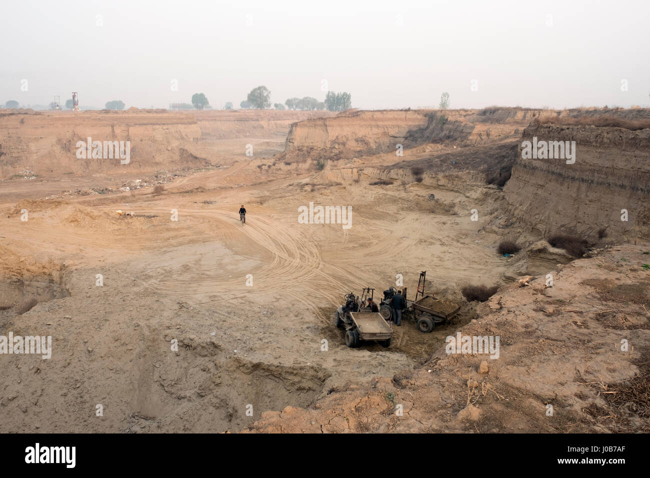 Men dredge earth or sand in a huge pit in Xiong County, Hebei province, China. 09-Apr-2017 Stock Photo