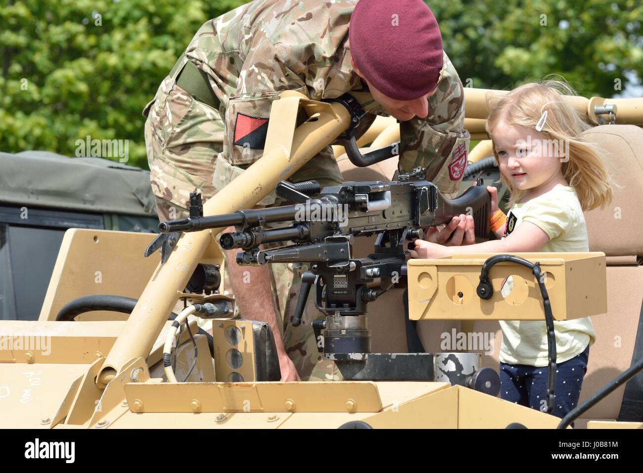 Military Tattoo  COLCHESTER ESSEX UK 8 July 2014:   Small Girl being shown gun by soldier Stock Photo