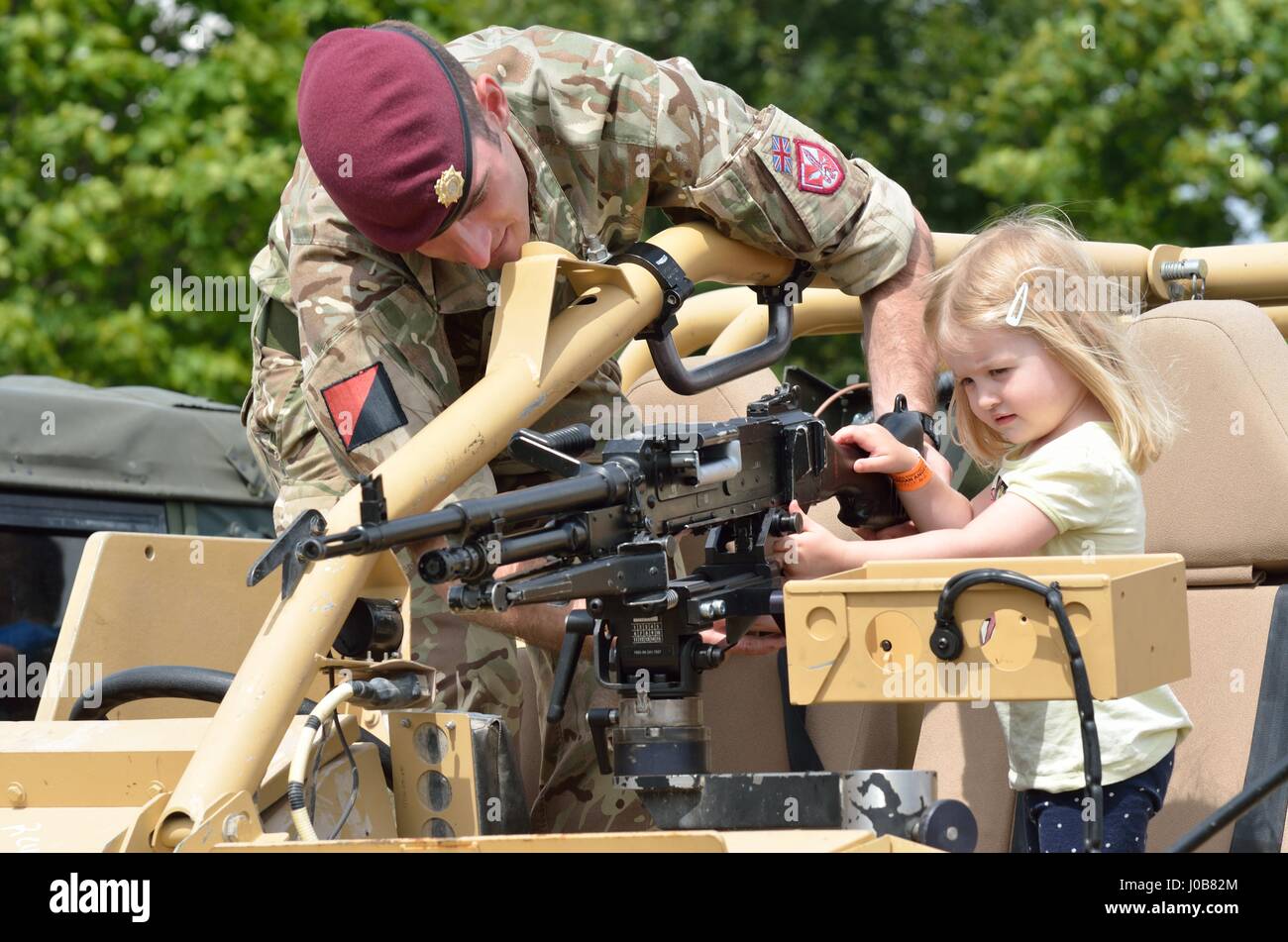 Military Tattoo  COLCHESTER ESSEX UK 8 July 2014:   Small Girl being shown machine gun by soldier Stock Photo