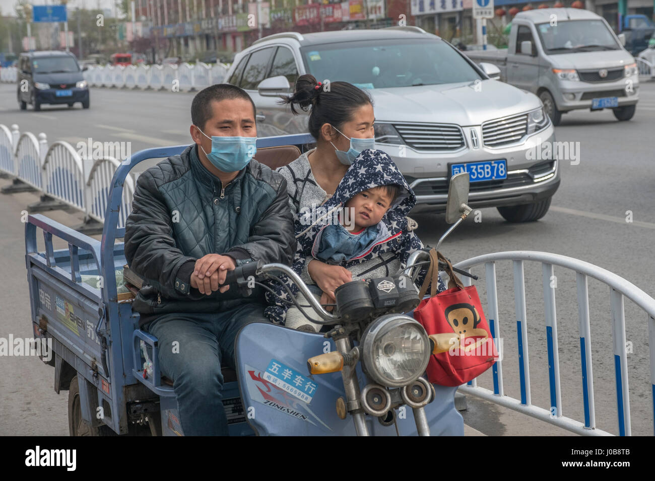 Chinese family of three on three-wheeled motorcycle in Xiong County, Hebei province, China. 09-APr-2017 Stock Photo