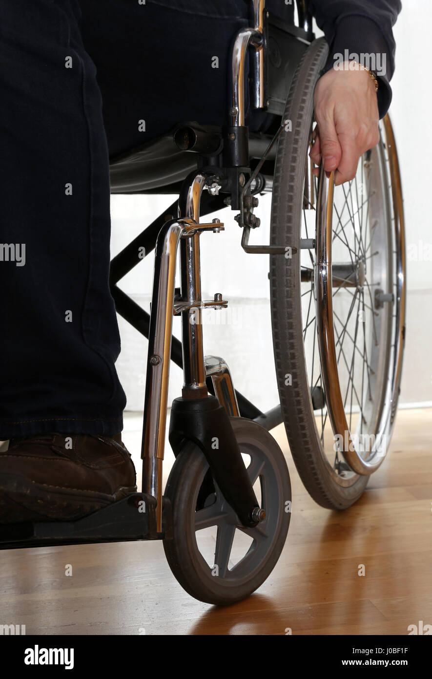 handicapped person in a wheelchair in his bedroom and hand on the wheel Stock Photo