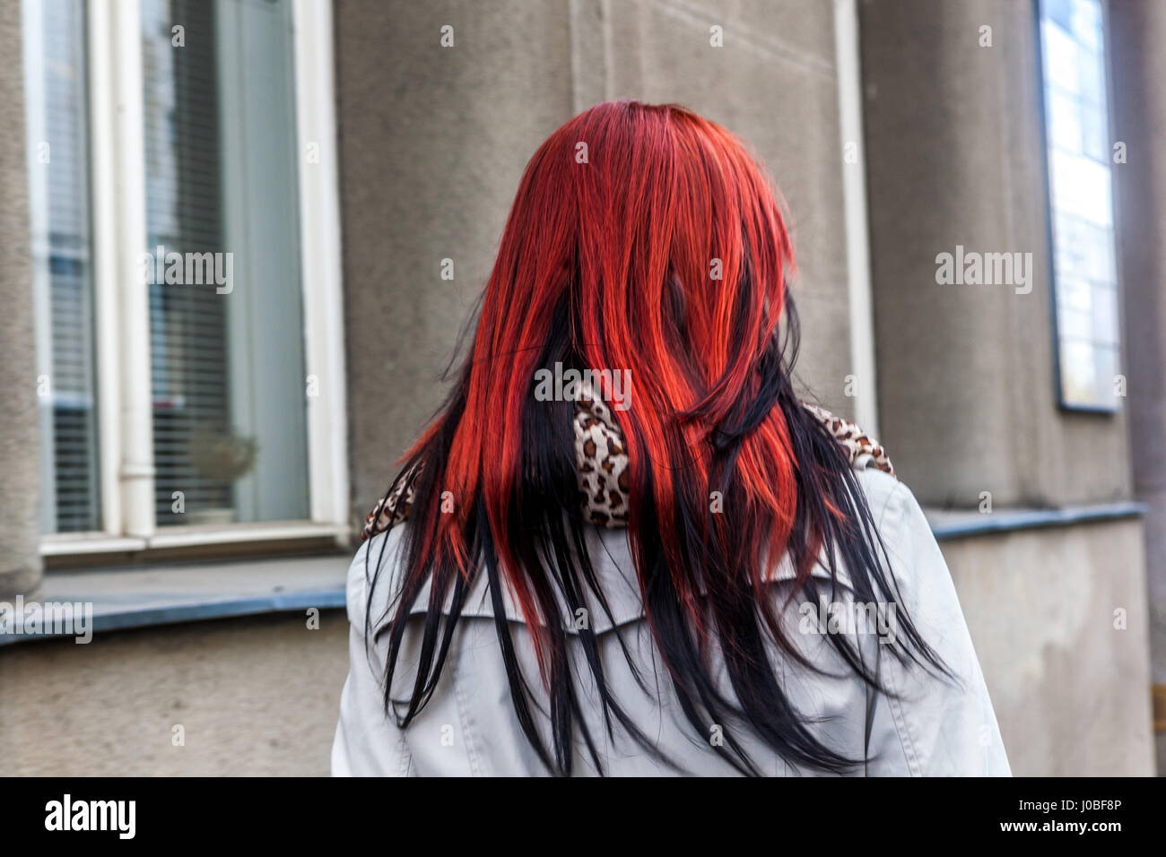 View of a woman from behind walking down the street with red and black hair Stock Photo