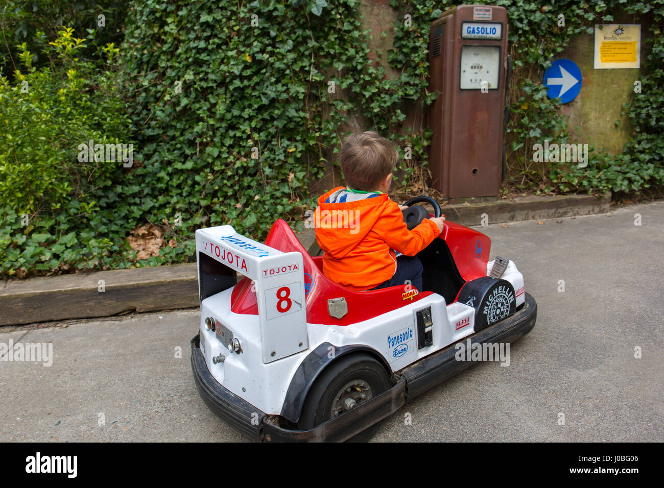 A kid (little boy / toddler) driving an electric toy car and pulling