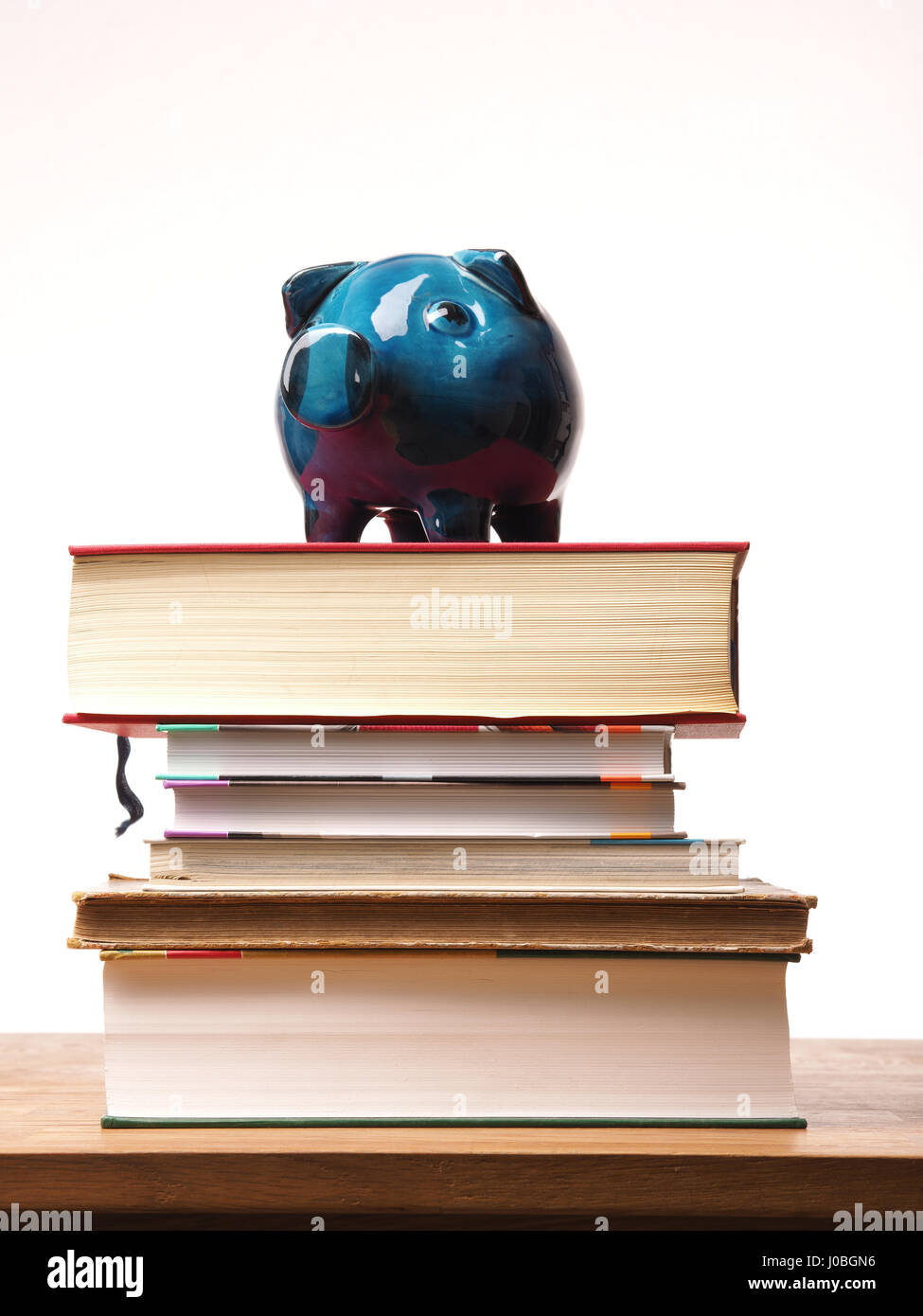 Old used ceramic piggy bank on a pile of books, financial concept Stock ...
