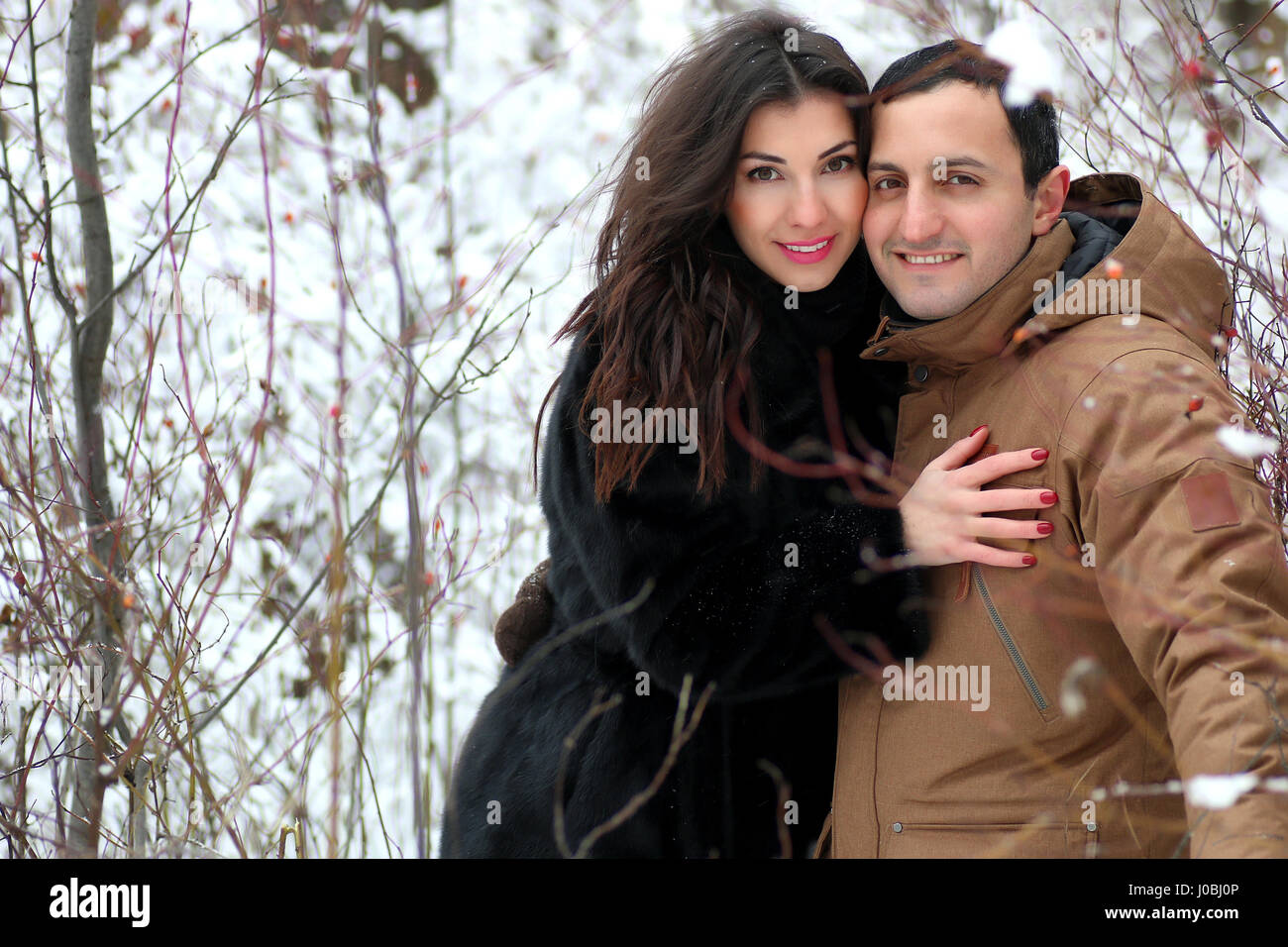 beautiful young couple in a snowy park wrapped Stock Photo - Alamy