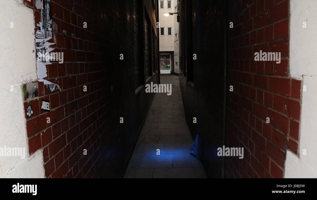 dark back alley with one blue light Stock Photo