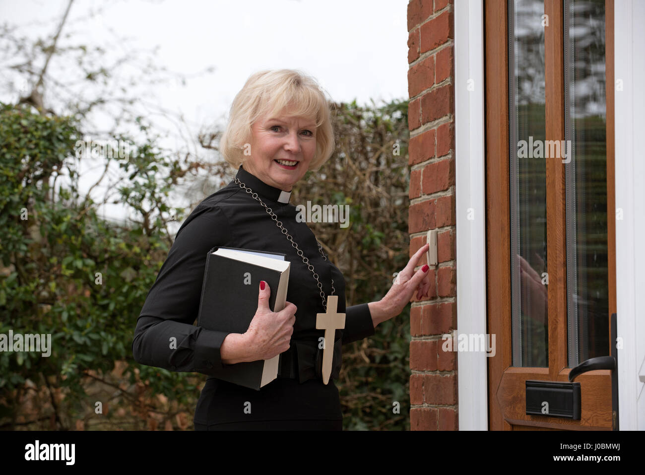 Elderly woman vicar making a house call in her parish in the English countryside Stock Photo