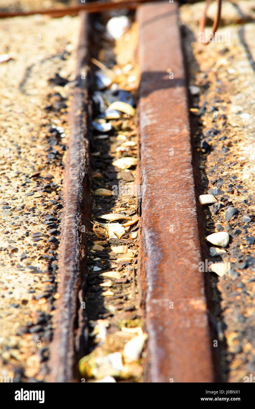 Old rusty railway track on Barge Pier - formerly Garrison Pier - at Shoeburyness, Southend, Essex, with broken sea shells Stock Photo