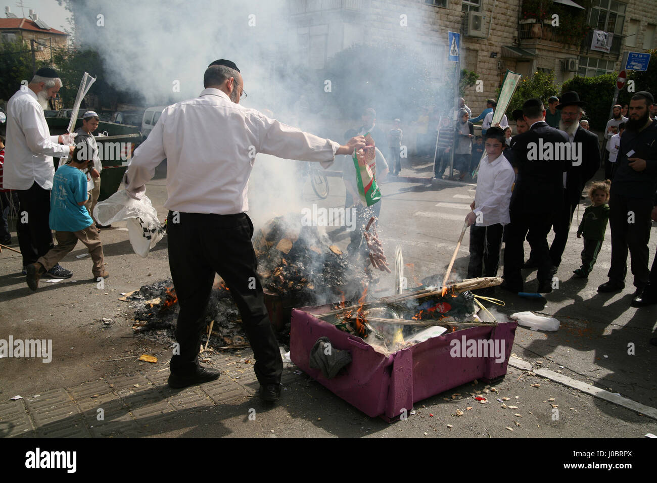Orthodox Jewish men burn Chametz, bread and foods, not Kosher for Passover in the morning of the eve of the holiday, here a man throws hotdogs in. Stock Photo