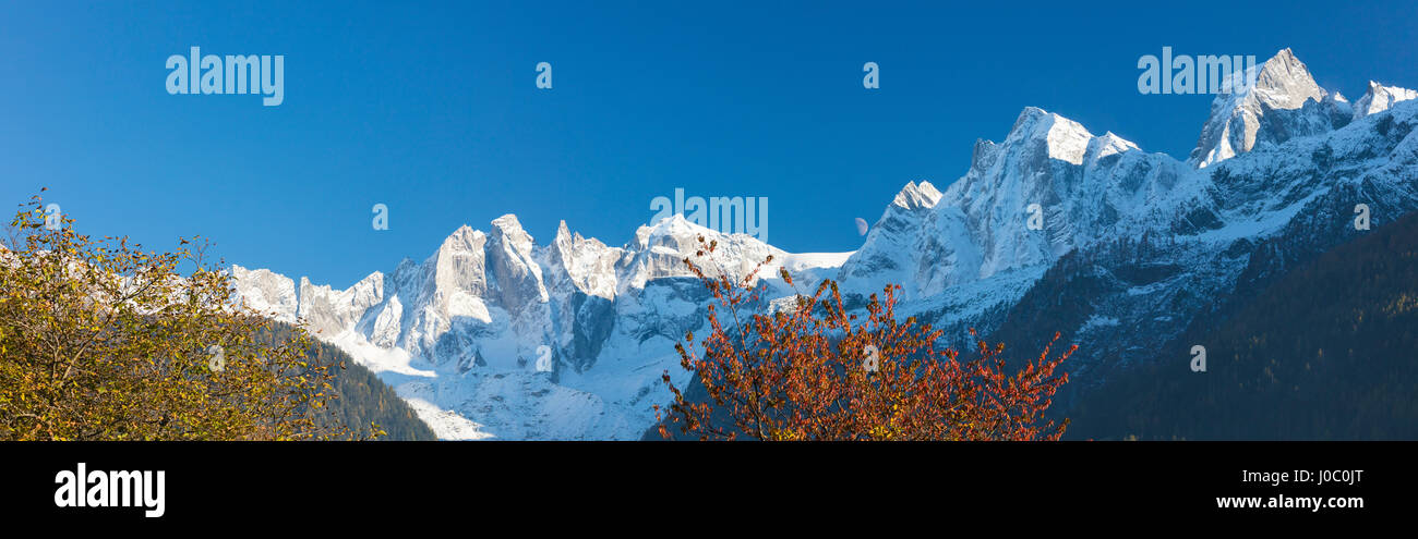 Panorama of the snowy peaks framed by colorful trees, Soglio, Bregaglia Valley, Canton of Graubunden, Switzerland Stock Photo