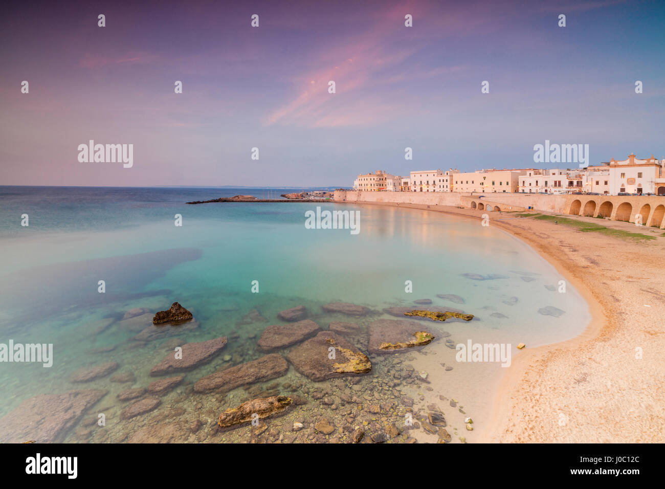 Turquoise sea frames the beach and the medieval old town at sunset Gallipoli, Province of Lecce, Apulia, Italy Stock Photo