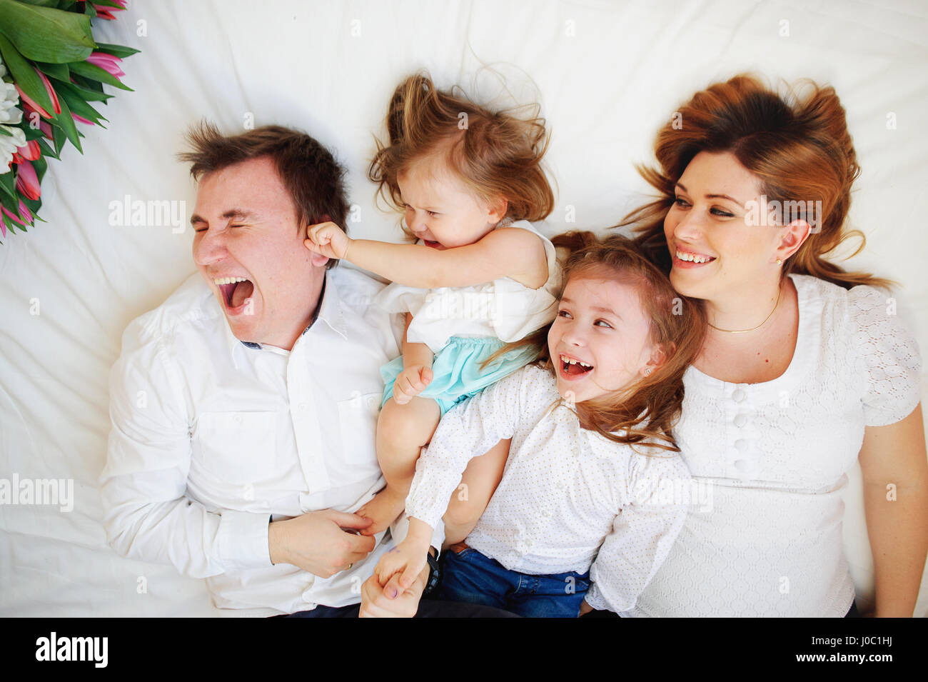 Big closeknit family from four people cheerfully spends time for beds
