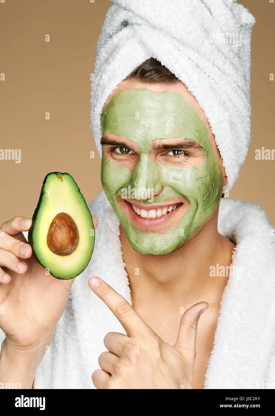 Happy smiling man with facial mask of avocado. Photo of well groomed man receiving spa treatments. Grooming himself Stock Photo