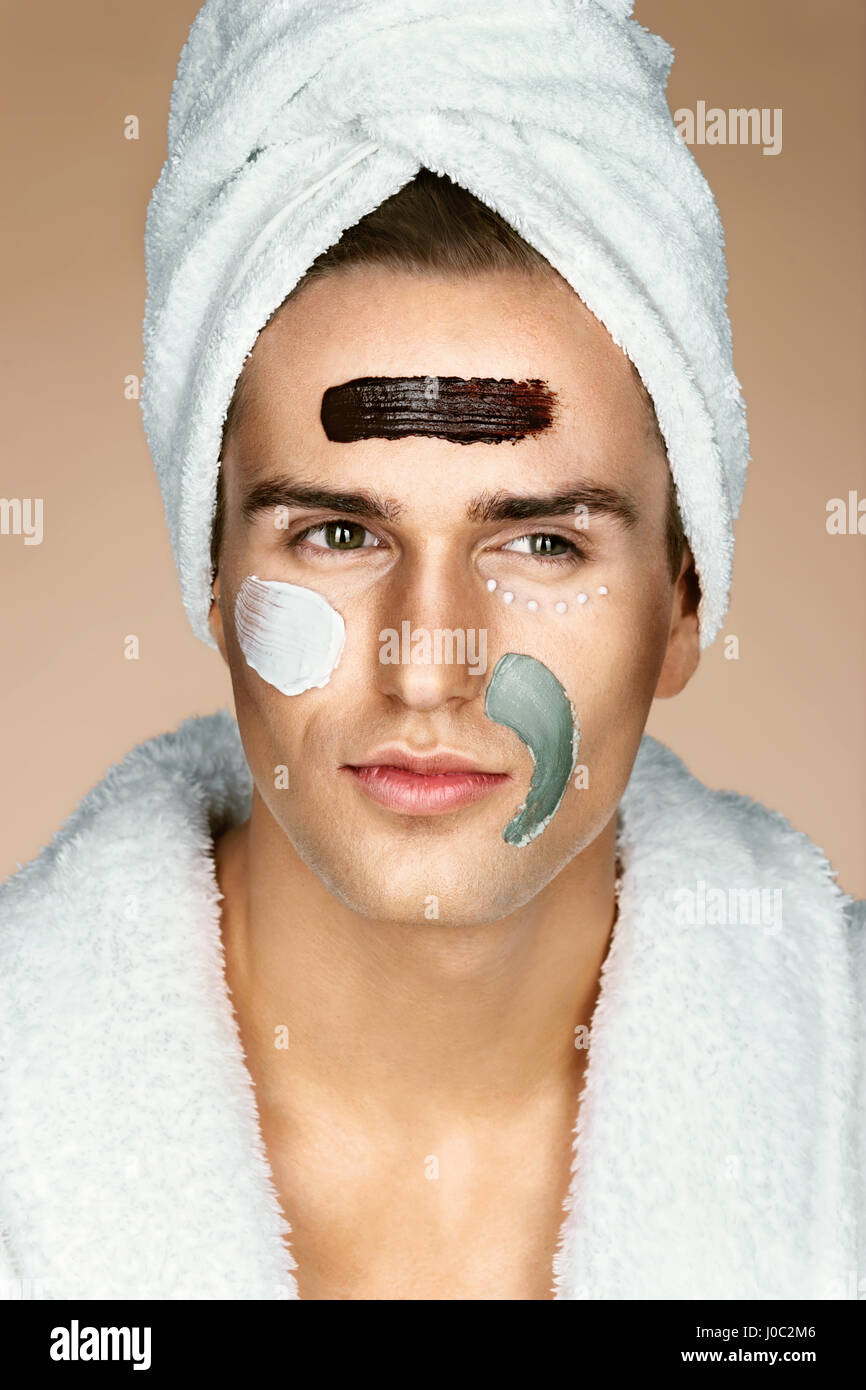 Fashionable man with three different face masks (chocolate, cream and clay masks). Photo of man with perfect skin. Grooming himself Stock Photo