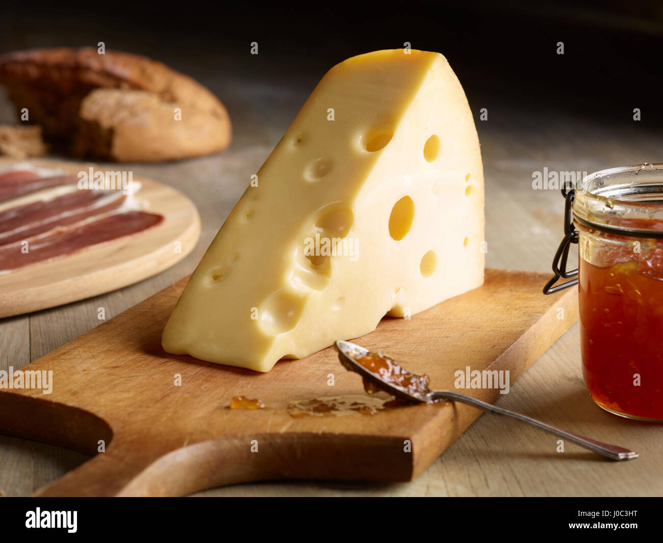 Still life of Edam cheese with quince chutney, on chopping board Stock Photo