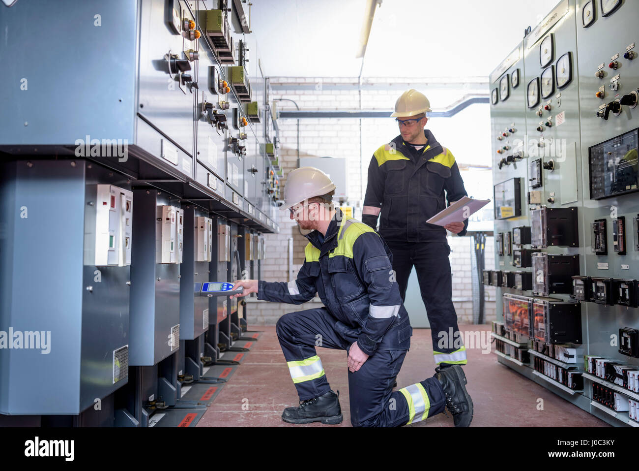 Workers testing for noise in electricity substation Stock Photo