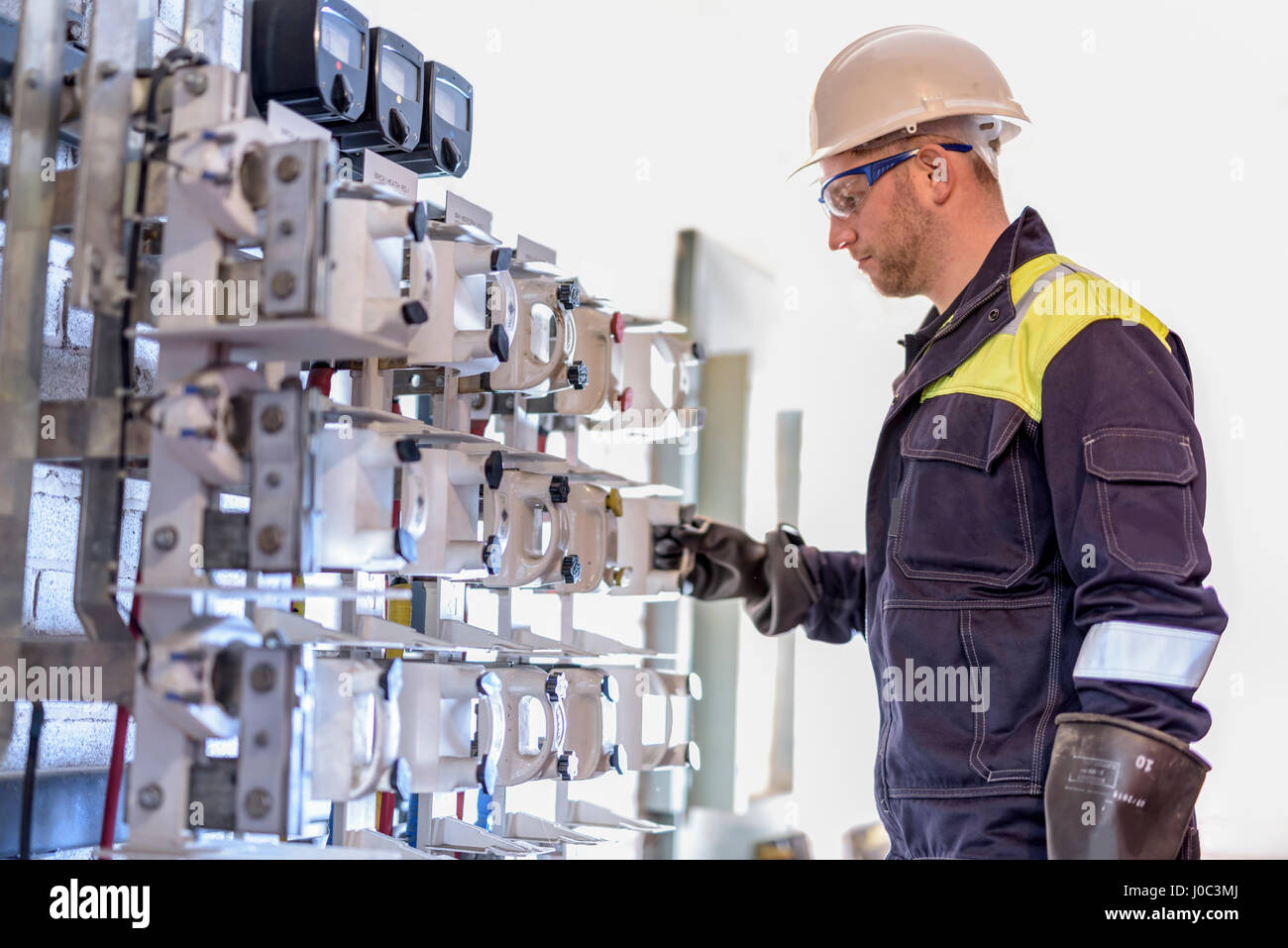Worker testing circuit breakers in electricity substation Stock Photo