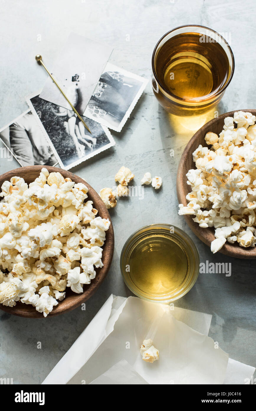 Still life of popcorn and drink, beside old black and white photographs, overhead view Stock Photo