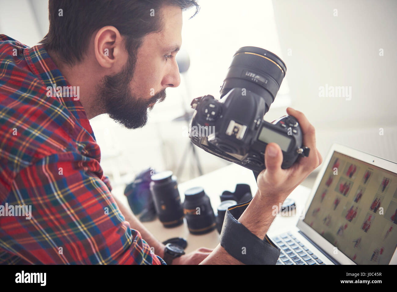 Male photographer reviewing photo shoot on laptop in studio Stock Photo